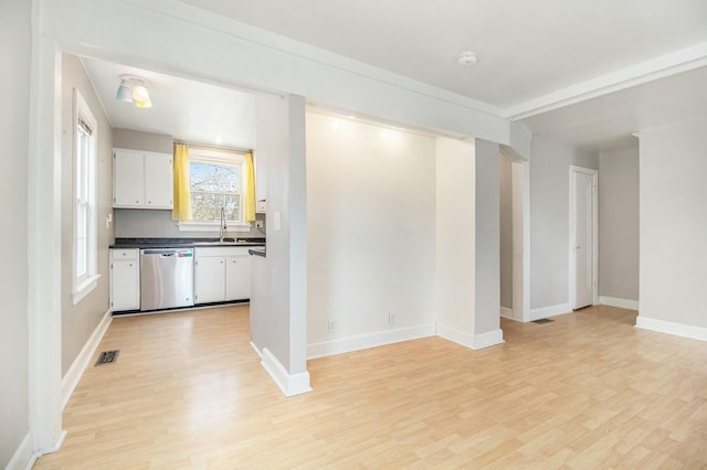 kitchen with white cabinets, dark countertops, dishwasher, and light wood-style flooring