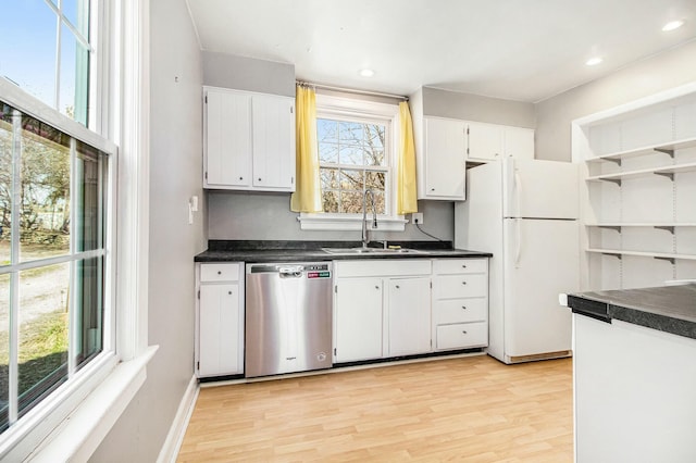 kitchen featuring open shelves, dark countertops, stainless steel dishwasher, a sink, and freestanding refrigerator