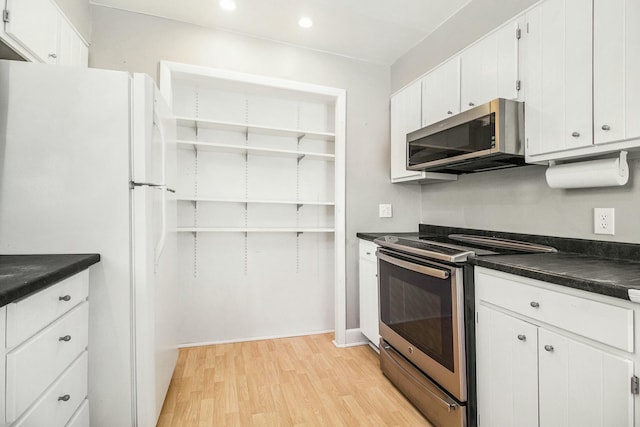 kitchen with dark countertops, light wood-style floors, stainless steel appliances, white cabinetry, and recessed lighting