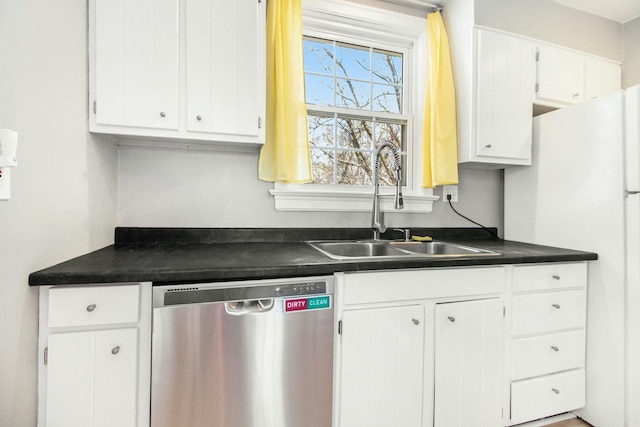 kitchen featuring dark countertops, stainless steel dishwasher, white cabinetry, and a sink