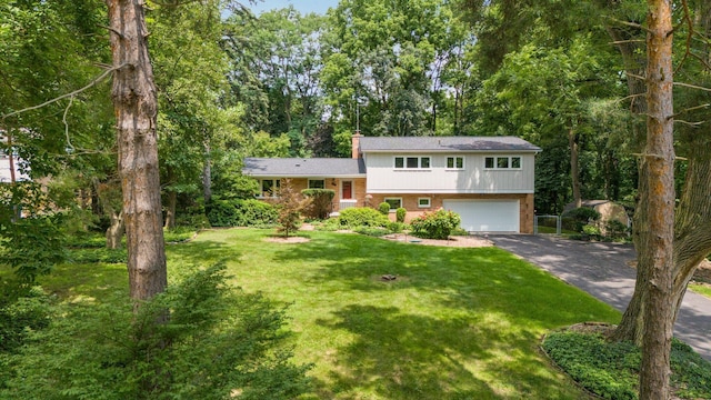 3091 Warwick Rd, Ann Arbor, MI 48104 - split level home featuring a chimney, aphalt driveway, an attached garage, a front yard, and brick siding