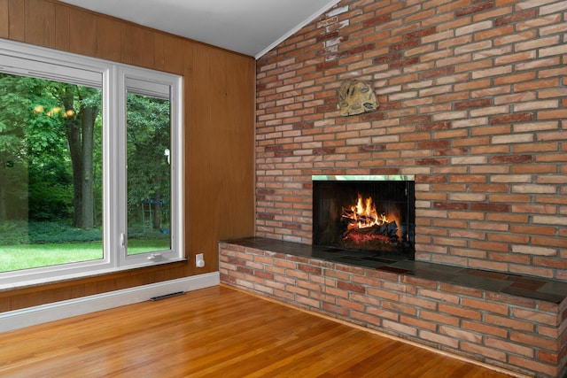 3091 Warwick Rd, Ann Arbor, MI 48104 - unfurnished living room featuring vaulted ceiling, visible vents, wood finished floors, crown molding, and a fireplace