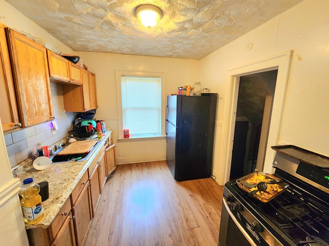 20117 Santa Rosa Dr, Detroit, MI 48221 - kitchen with stainless steel gas range, freestanding refrigerator, light wood-style floors, backsplash, and a sink