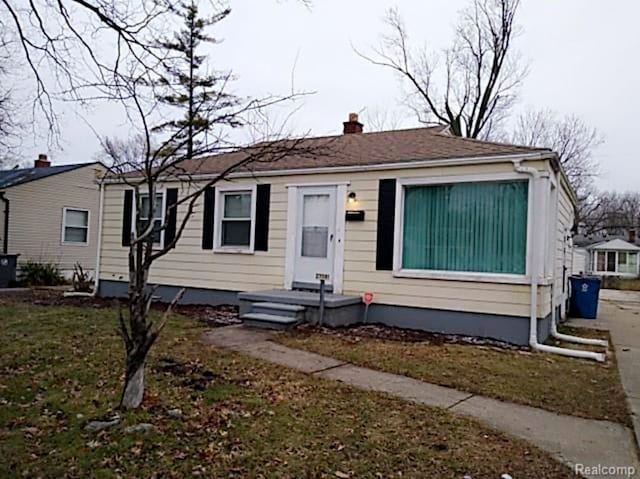 view of front of house with a chimney and a front yard