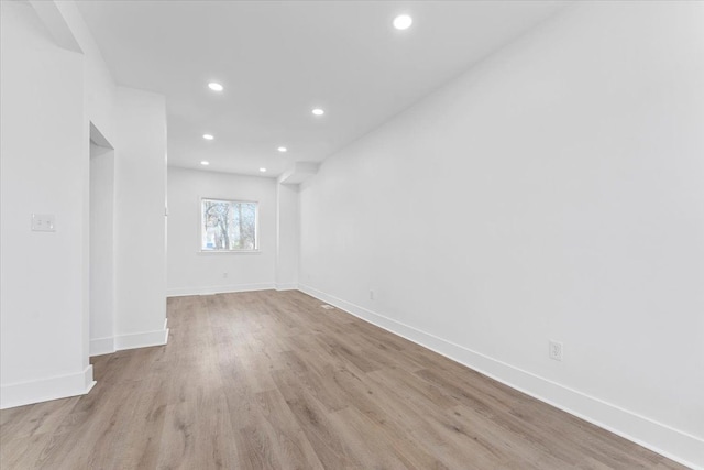 empty room with baseboards, wood finished floors, and recessed lighting