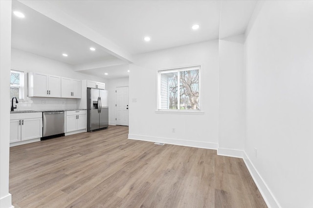 unfurnished living room with recessed lighting, light wood-type flooring, and baseboards