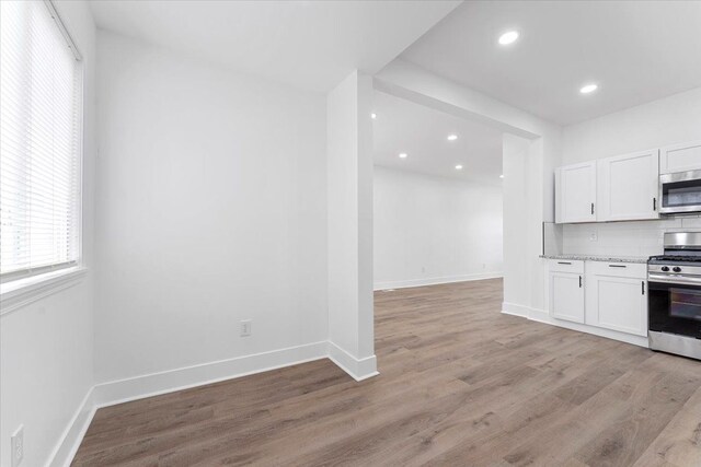 kitchen featuring white cabinets, decorative backsplash, appliances with stainless steel finishes, and light wood finished floors