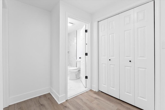 interior space with toilet, a closet, wood finished floors, and baseboards