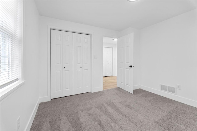 unfurnished bedroom with carpet floors, a closet, visible vents, and baseboards