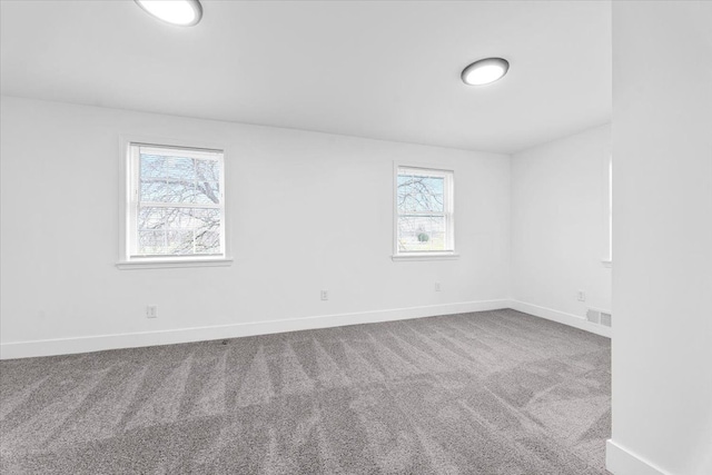 empty room featuring baseboards, visible vents, and carpet