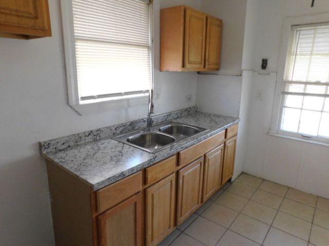15864 Bringard Dr, Detroit, MI 48205 - kitchen with light countertops, a sink, brown cabinets, and light tile patterned floors