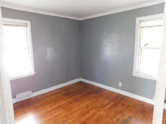 15864 Bringard Dr, Detroit, MI 48205 - empty room with wood finished floors, visible vents, crown molding, and baseboards