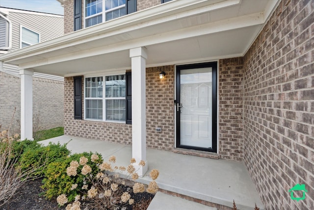 doorway to property with covered porch and brick siding