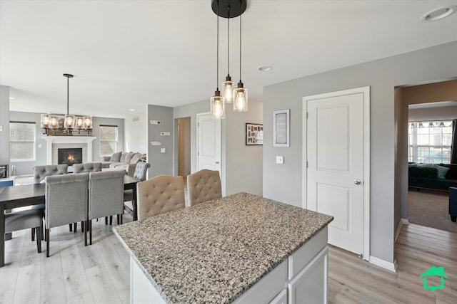 interior space with a chandelier, a lit fireplace, light wood-style flooring, baseboards, and recessed lighting