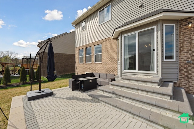 rear view of house with brick siding, a yard, an outdoor living space with a fire pit, and a patio