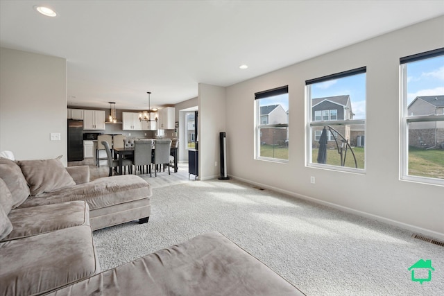 living area featuring recessed lighting, an inviting chandelier, visible vents, baseboards, and light colored carpet