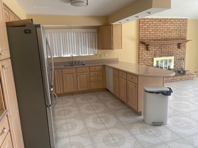 kitchen featuring light brown cabinets, freestanding refrigerator, dishwasher, a sink, and a peninsula