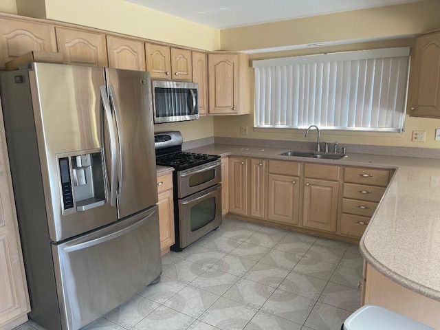 kitchen with light brown cabinets, appliances with stainless steel finishes, light countertops, and a sink