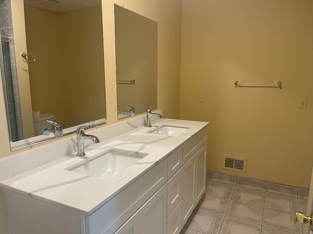 full bath featuring double vanity, visible vents, toilet, and a sink