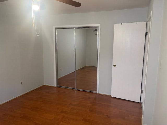 unfurnished bedroom featuring ceiling fan, wood finished floors, and a closet