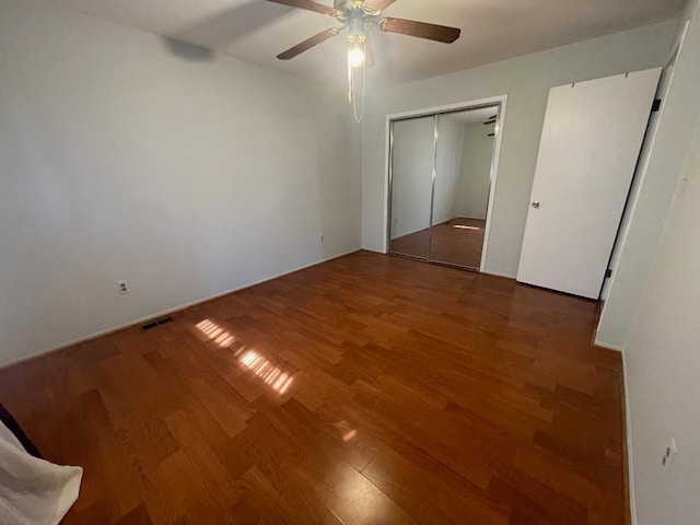 unfurnished bedroom with a closet, wood finished floors, visible vents, and ceiling fan