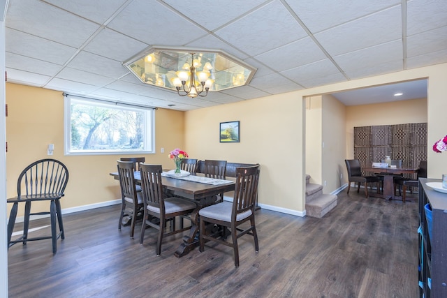 dining room featuring wood finished floors, baseboards, a paneled ceiling, and an inviting chandelier