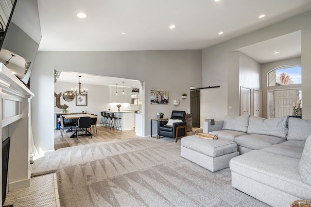 carpeted living area with high vaulted ceiling, an inviting chandelier, a fireplace, baseboards, and recessed lighting