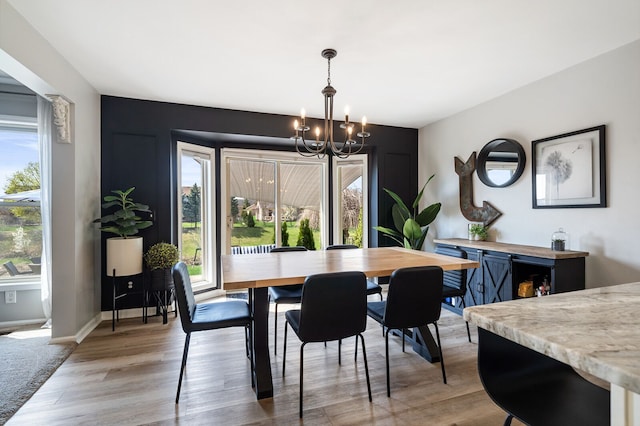 dining area with light wood-type flooring, baseboards, and a notable chandelier