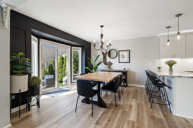 dining area with baseboards, an inviting chandelier, and light wood-style floors