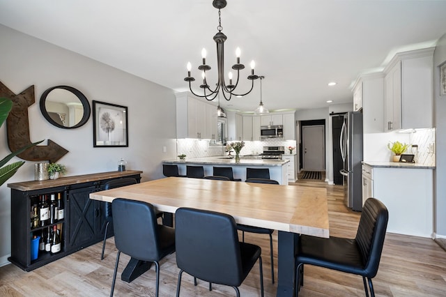 dining space with light wood finished floors, recessed lighting, and a chandelier