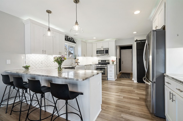 kitchen featuring a peninsula, tasteful backsplash, white cabinetry, and stainless steel appliances