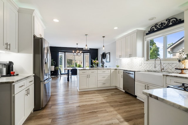 kitchen with white cabinets, a peninsula, stainless steel appliances, and a sink
