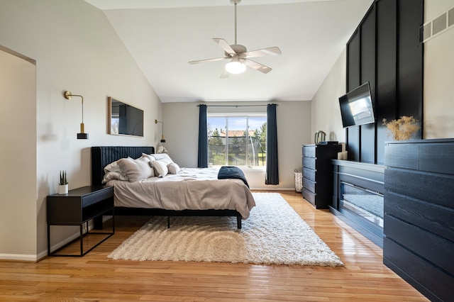 bedroom featuring light wood-style floors, lofted ceiling, baseboards, and ceiling fan