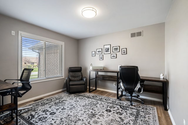 office area with baseboards, wood finished floors, and visible vents