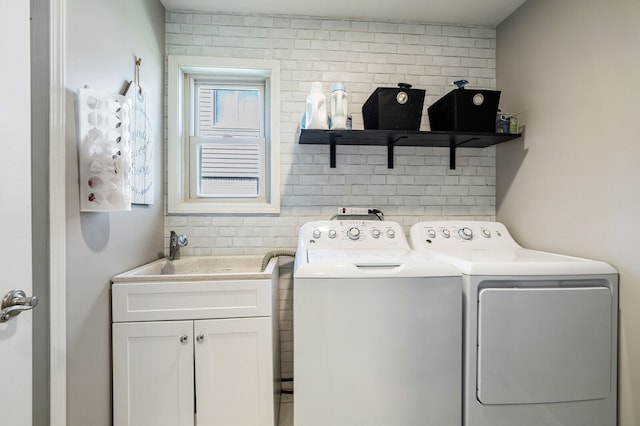 laundry room with washing machine and clothes dryer, cabinet space, and a sink