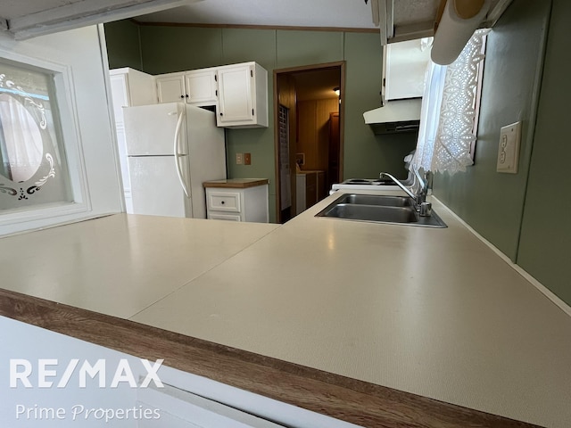 kitchen with freestanding refrigerator, a sink, white cabinetry, a peninsula, and ventilation hood