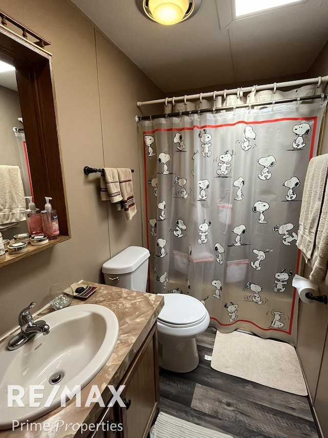 bathroom with curtained shower, wood finished floors, toilet, and vanity