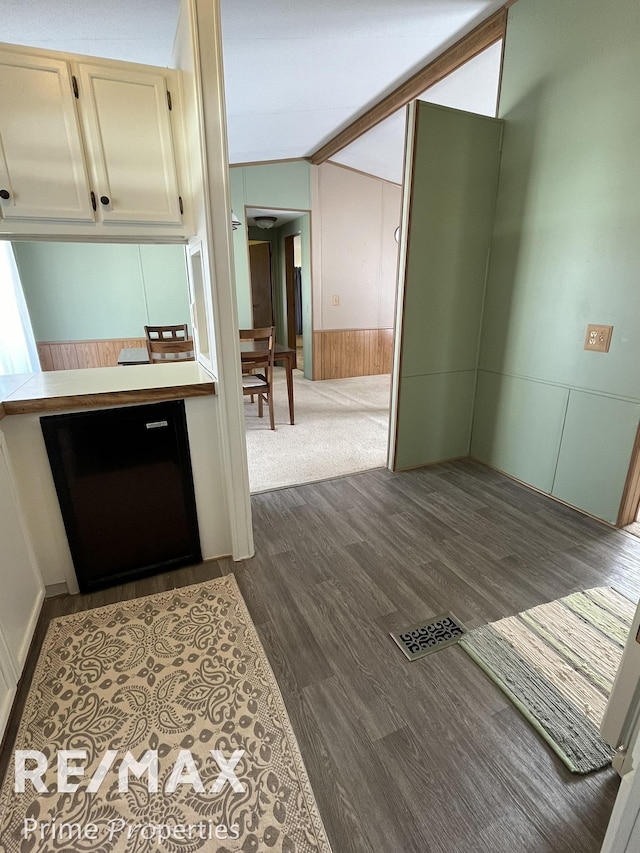 kitchen with dark wood-style flooring, wainscoting, vaulted ceiling, and light countertops