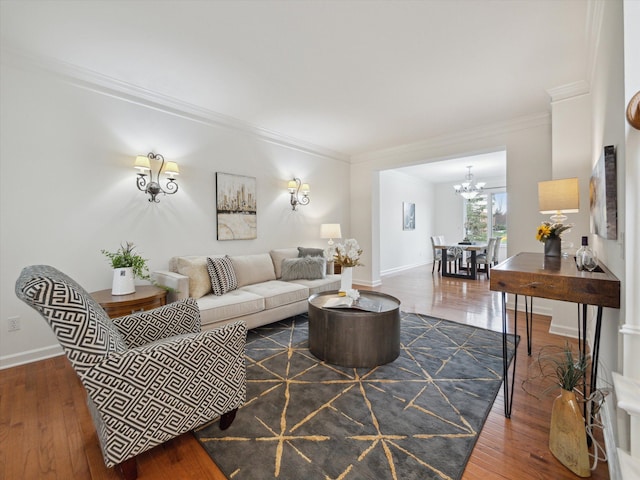 living room with baseboards, a notable chandelier, wood finished floors, and crown molding