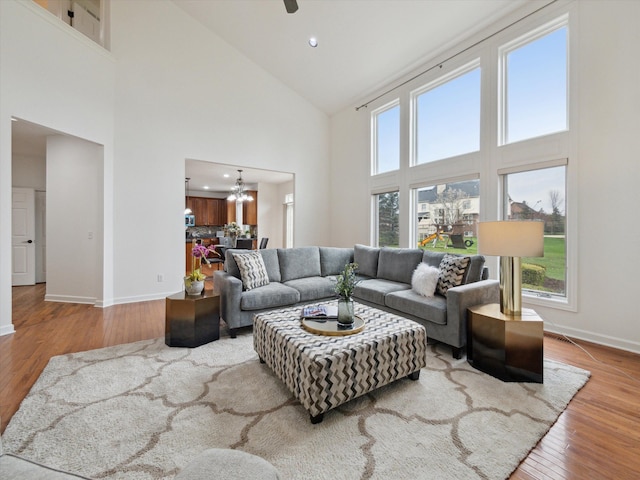 living area with a wealth of natural light, wood finished floors, baseboards, and high vaulted ceiling