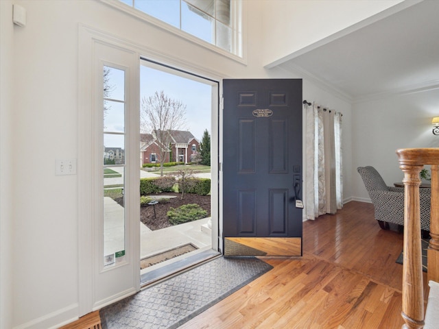 entrance foyer with baseboards, crown molding, wood finished floors, and plenty of natural light