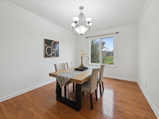dining room with a notable chandelier, crown molding, and light wood-style floors