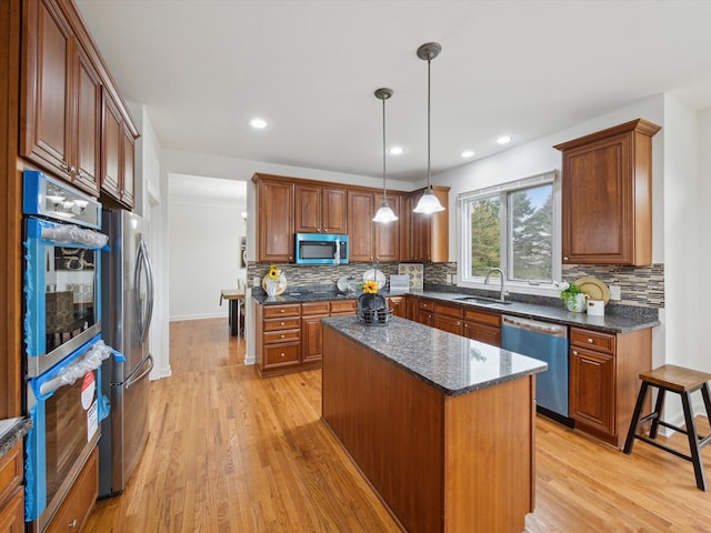 kitchen featuring decorative backsplash, stainless steel appliances, light wood-style flooring, and a sink