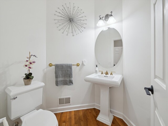 bathroom featuring baseboards, wood finished floors, visible vents, and toilet