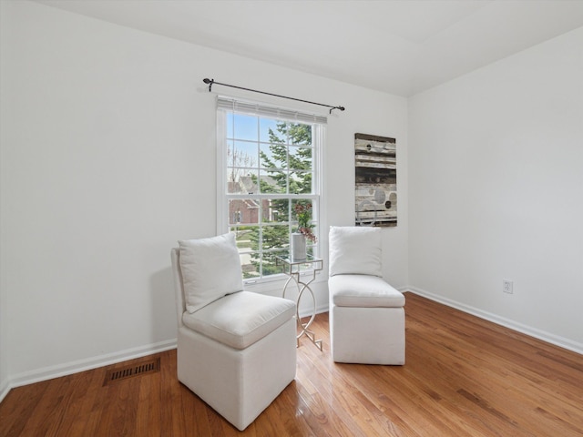 sitting room featuring wood finished floors, visible vents, and baseboards