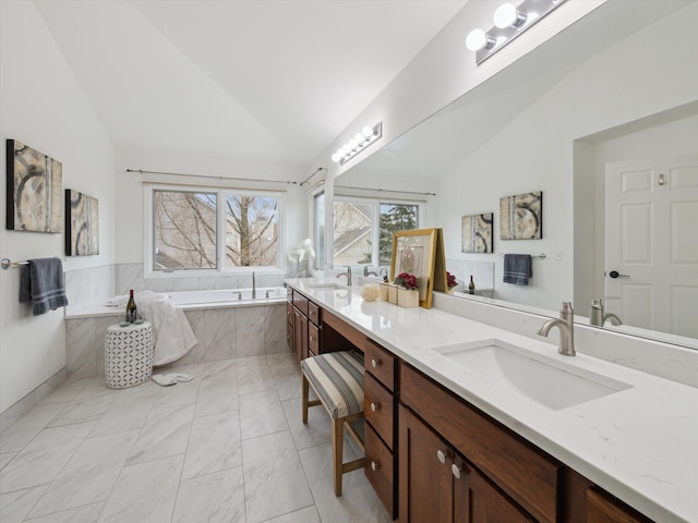 bathroom featuring double vanity, vaulted ceiling, a garden tub, and a sink