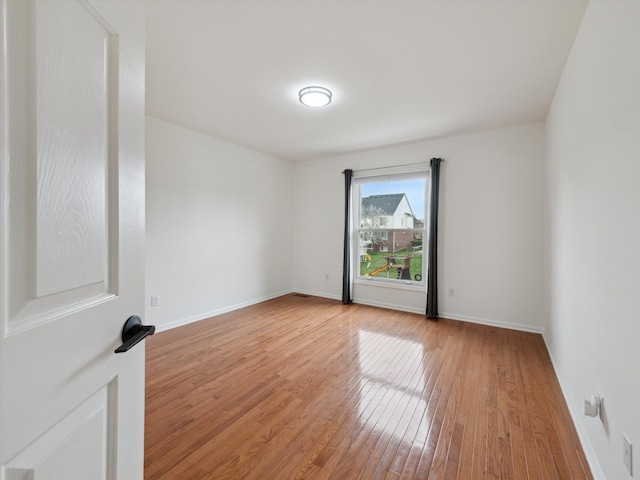 spare room with baseboards and light wood-style floors