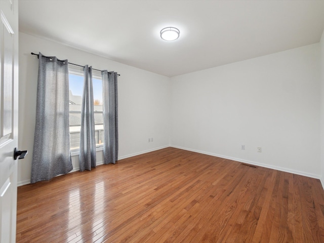 unfurnished room featuring baseboards, visible vents, and light wood-style flooring