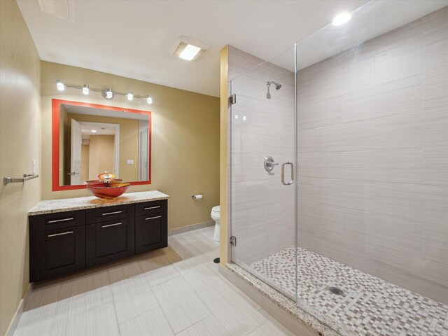 bathroom with baseboards, a shower stall, toilet, and vanity