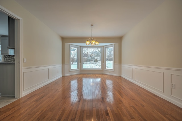 4238 Still Meadow Ln, West Bloomfield, MI 48323 - unfurnished dining area featuring a chandelier, wood-type flooring, wainscoting, and a decorative wall